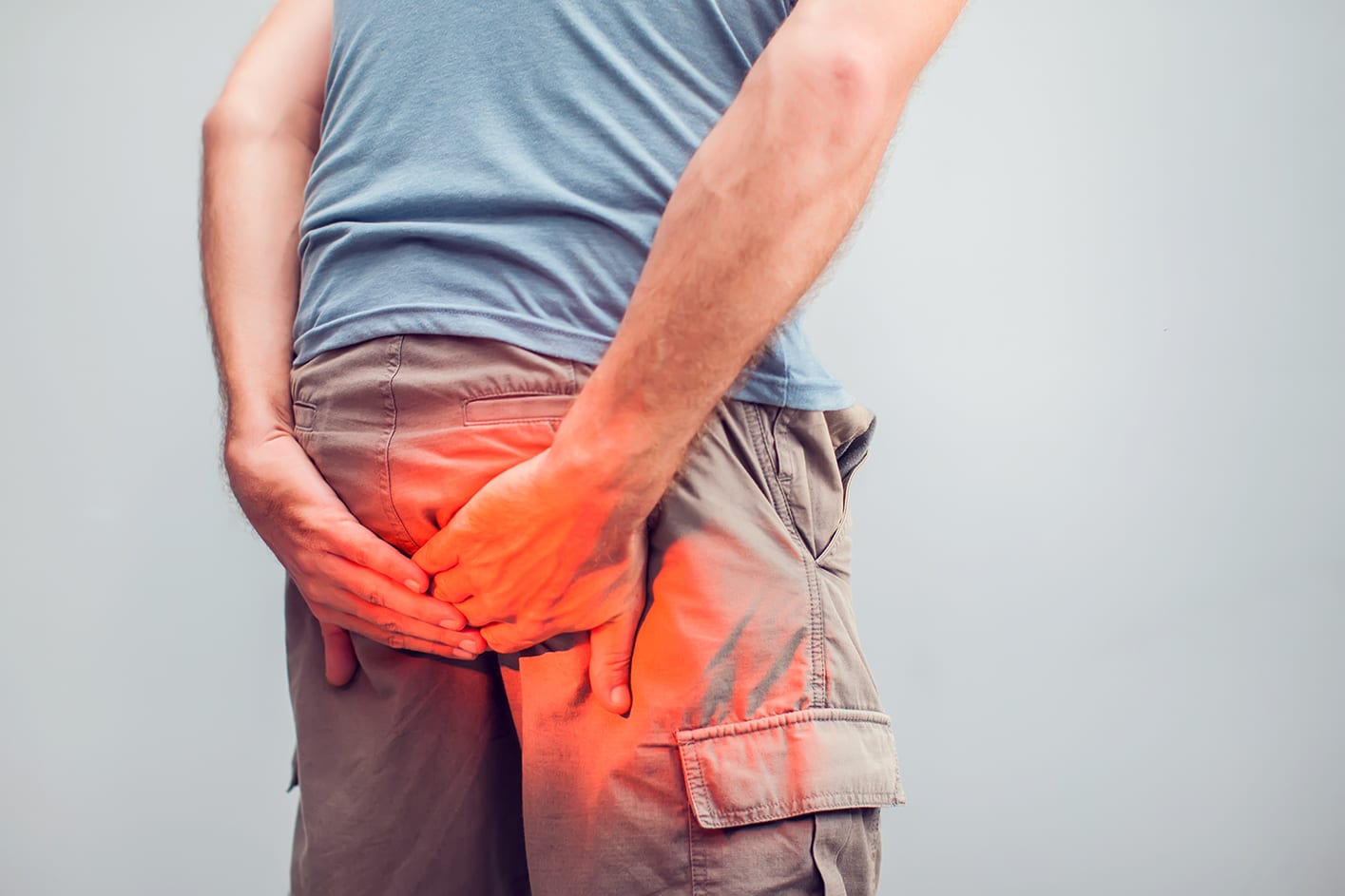 Man with hemorrhoids holding his butt in pain, in a white background